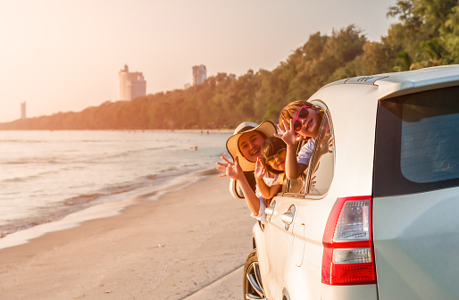 Car on the beach, where family is waving 