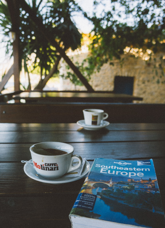 Travelling book laying on a table with a cup of coffee.