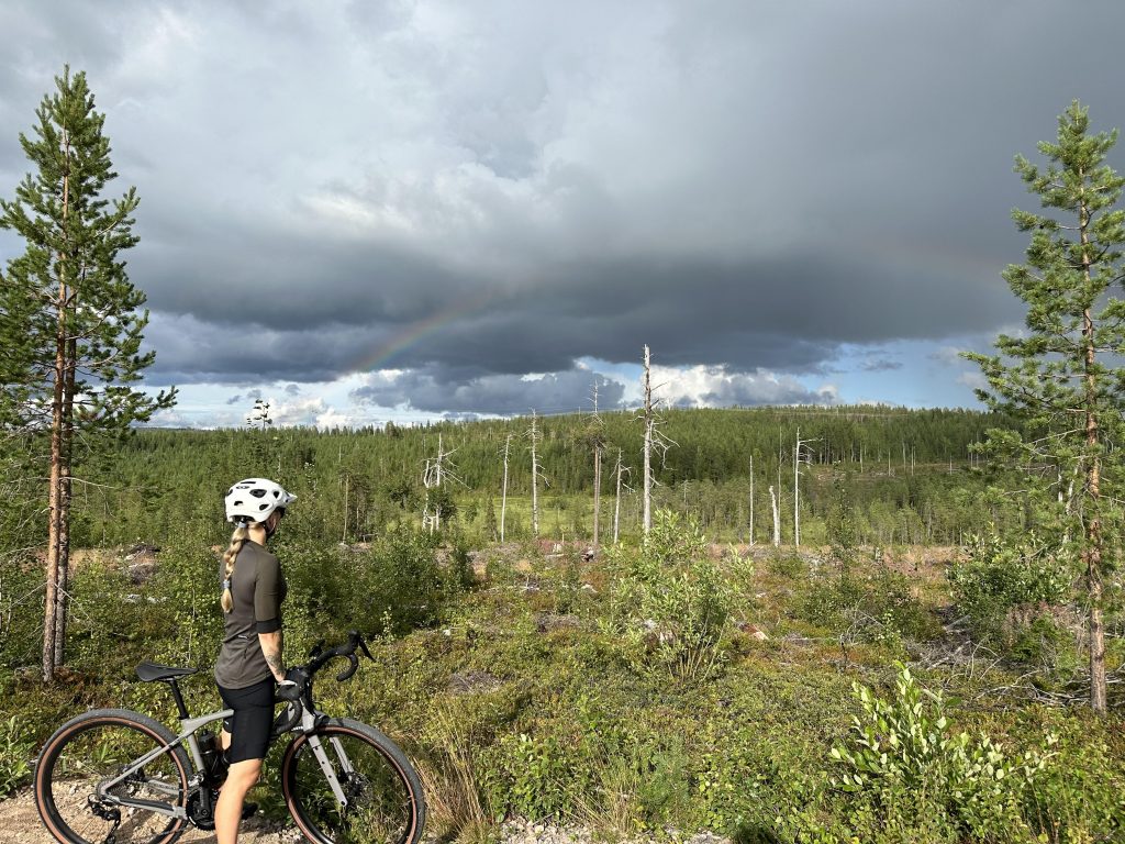 Gravel biker in the forest looking a rainbow. 