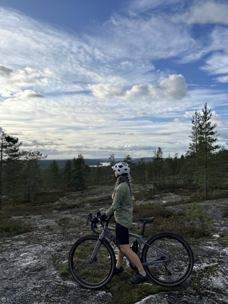 Gravel biker looks at the Ounasjoki-river landscape. 
