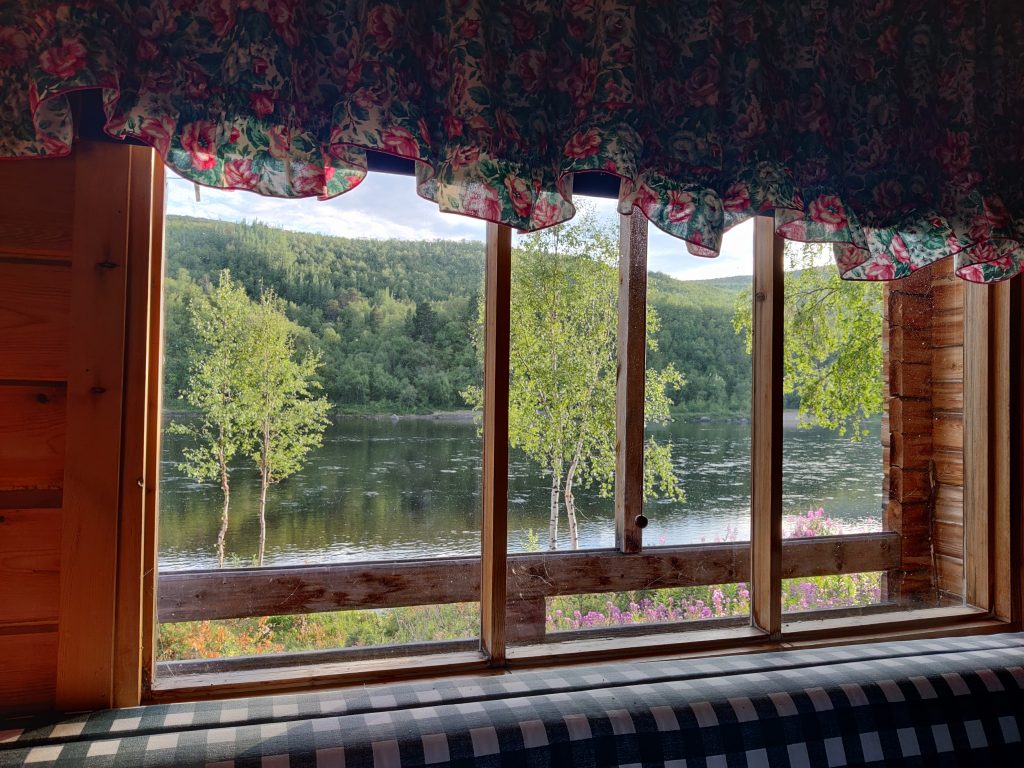 The river Teno flows peacefully past the log cabin.