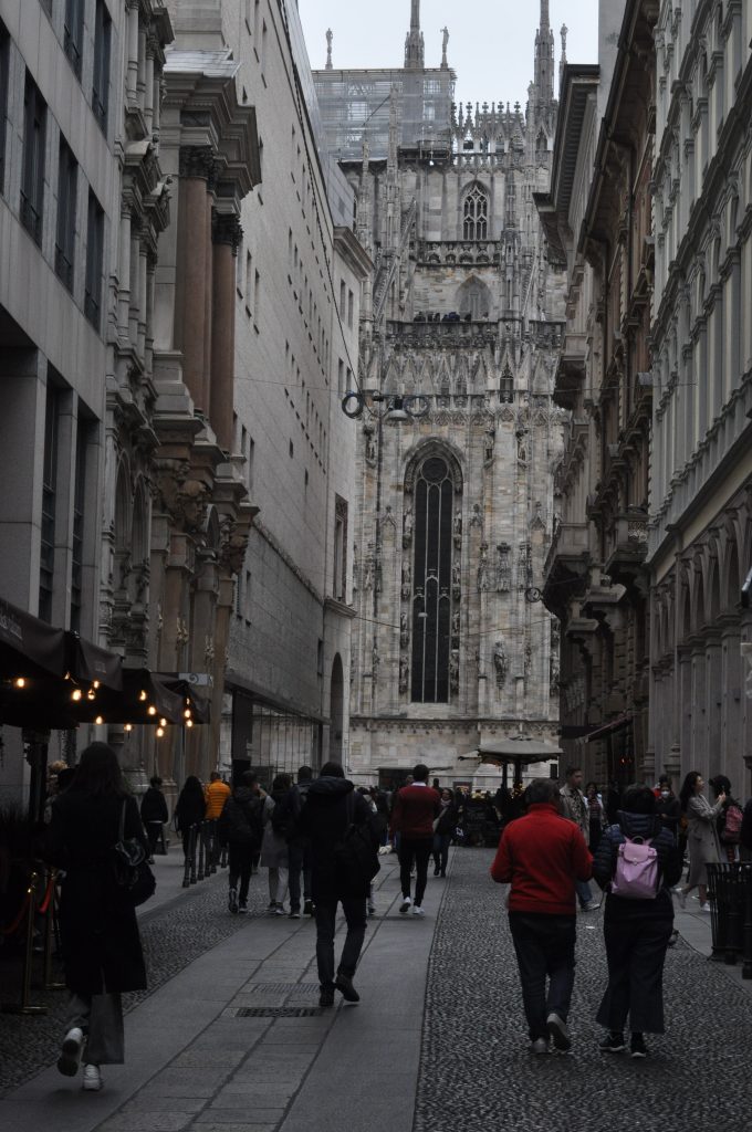 Street view of Duomo district. The street is lively and surrounded by old Italian architecture.