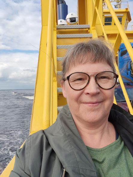 Women guide in the ferry to Hailuoto. Yellow structures of ferry and the grey sea in the background.
