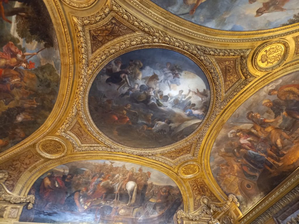Ceiling from one of the rooms in Versailles.Golden details together with fresco paintings.
