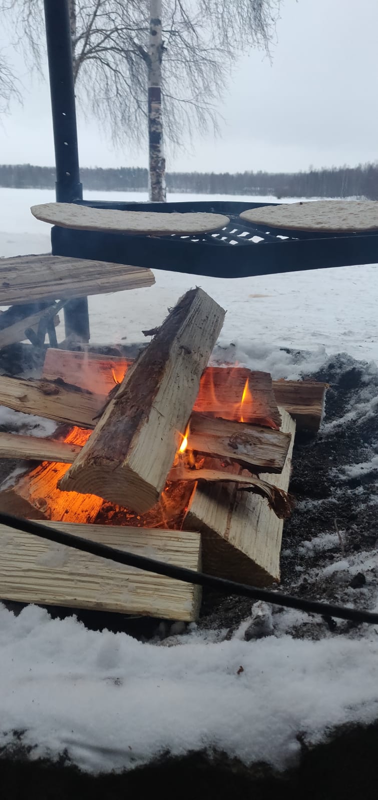 nuotion päällä ritillällä kaksi pitsapohjaa, taustalla talvinen maisema.