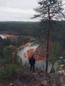 A person standing on the edge and looking at the winding river in Oulanka national park in Lapland. 