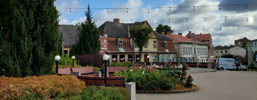 Garden area in the old market square of Tukums with buildings in the back.