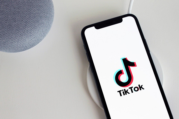 Smartphone on a table. It has a white screen with the TikTok logo on it.