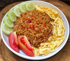 Traditional nasi goreng - Fried rice with tomatoes, cucumber and eggs