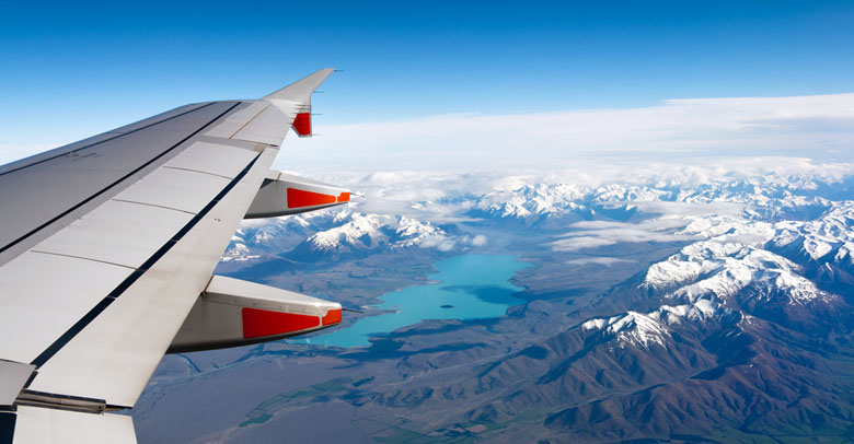 View from a flying plane over snowy mountains.