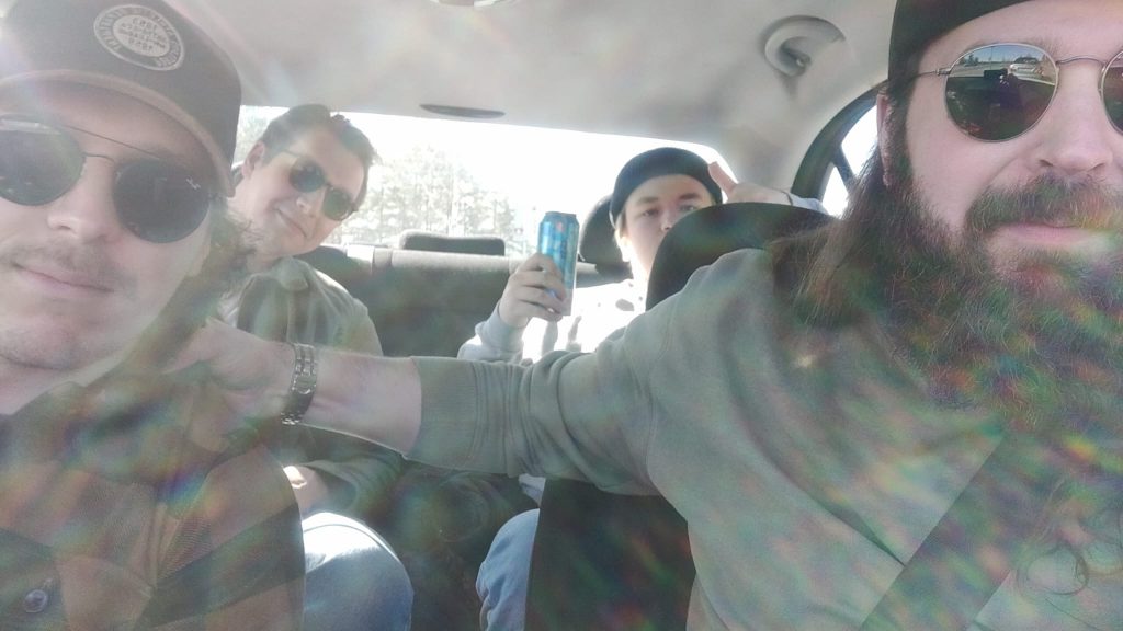 Fabian, Paavo, Calle ja Ykä istumassa hymyillen autossa.