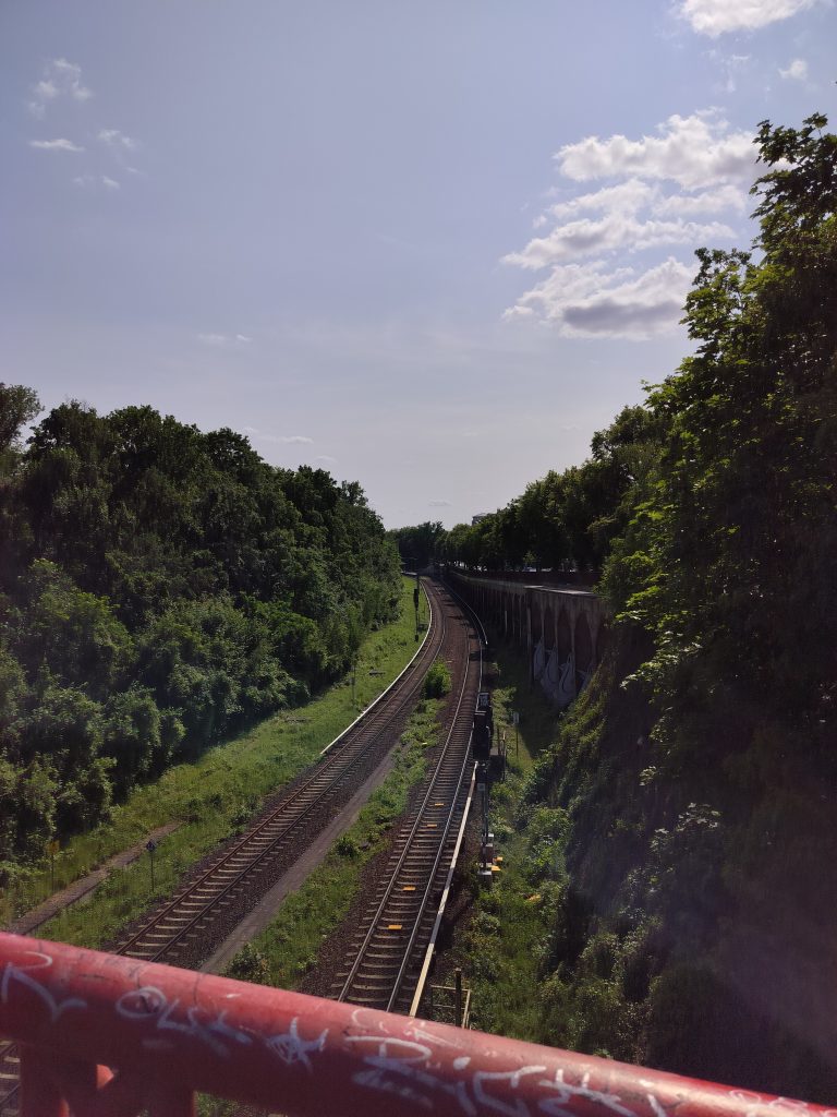 Kaksi tyhjää junarataa Berliinissä, puun vihreyden ympäröimänä.